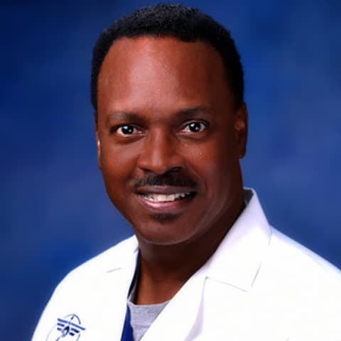 Smiling Black man with a mustache wearing a white lab coat against a blue background.