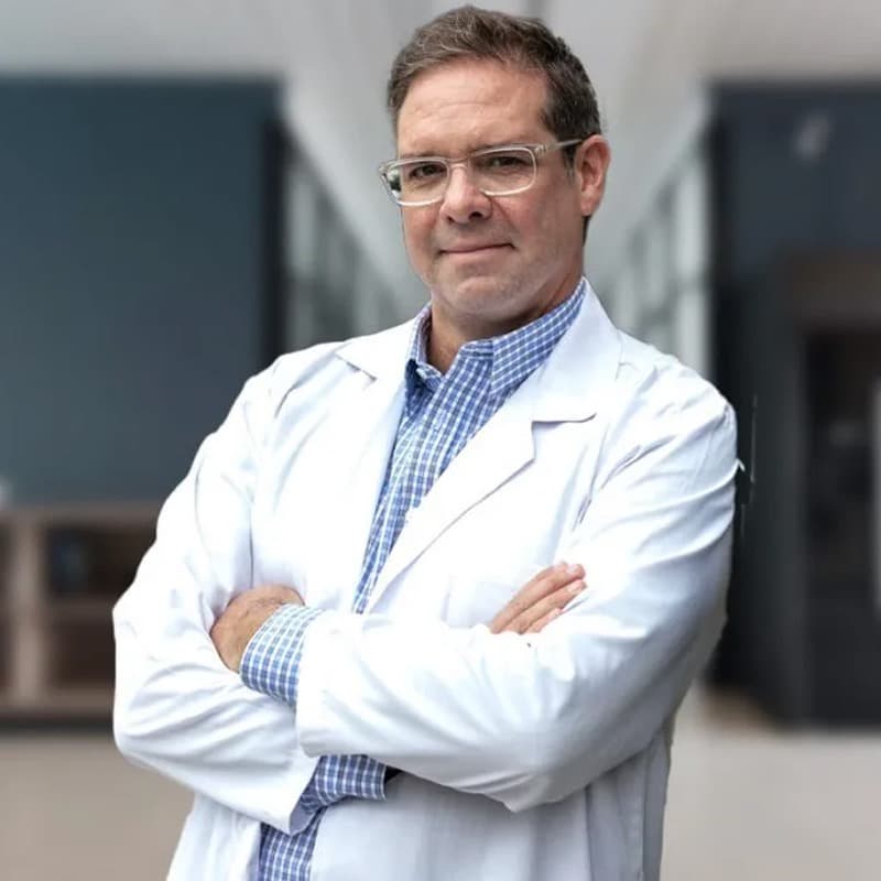 A male doctor wearing glasses and a white lab coat with arms crossed.